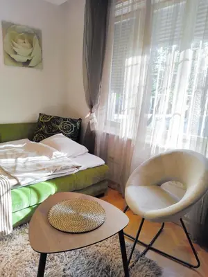 a bedroom with a bed and a chair and a table at Studio apartment CENTER in Podgorica