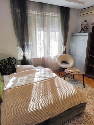 a bedroom with a bed and a chair and a window at Studio apartment CENTER in Podgorica