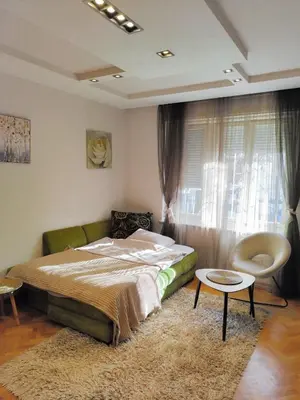 a bedroom with a bed and a chair and a window at Studio apartment CENTER in Podgorica