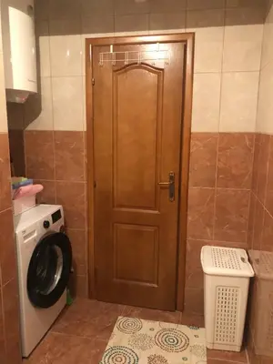a wooden door in a bathroom with a washing machine at Lina Apartment in Bar