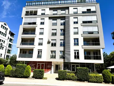 a tall white building with bushes in front of it at Renta Stanovi Podgorica in Podgorica