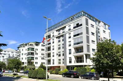 a white building with cars parked in front of it at Renta Stanovi Podgorica in Podgorica