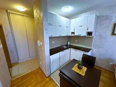 a small kitchen with white cabinets and a table at Renta Stanovi Podgorica in Podgorica