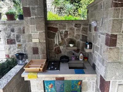 a outdoor kitchen with a stove and a stone wall at Stone Villa Guesthouse in Budva