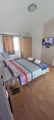 a bedroom with a large bed with a wooden floor at Apartments Kalamperovic in Bar