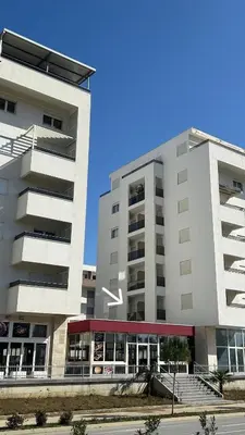 a large white building next to a tall building at Apartment Lotus in Ulcinj