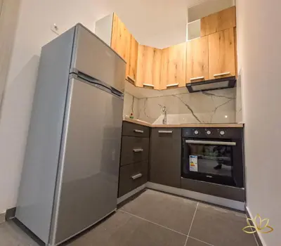 a kitchen with a stainless steel refrigerator and wooden cabinets at Apartment Lotus in Ulcinj