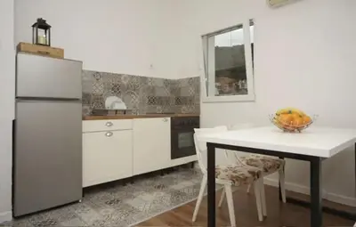a kitchen with a refrigerator and a table with a bowl of fruit at Casa Calda apartman in Budva