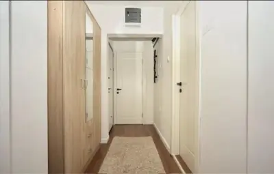 a hallway with white walls and white doors and a rug at Casa Calda apartman in Budva