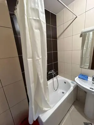 a bathroom with a shower curtain and a tub and a sink at Stylish_apartment in Podgorica