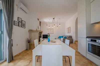 a kitchen and living room with a white table and chairs at Vacation home in Budva near the beach in Krimovice