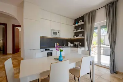 a white dining room with a table and chairs at Vacation home in Budva near the beach in Krimovice