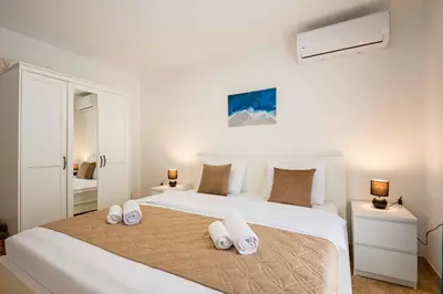 a white bedroom with a large white bed with white pillows at Vacation home in Budva near the beach in Krimovice