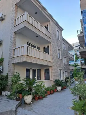 a apartment building with a balcony and potted plants at Apartments Djuro in Petrovac na Moru