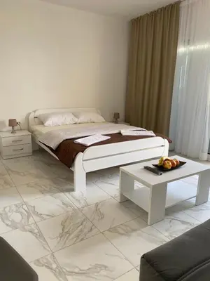 a white bedroom with a bed and a table at Apartmani Vila Delfin in Dobra Voda