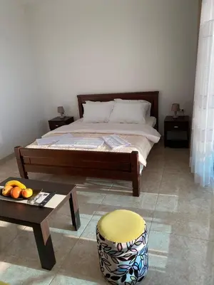 a bedroom with a bed and a table and a stool at Apartmani Vila Delfin in Dobra Voda
