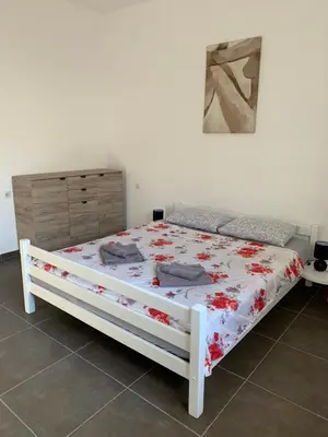 a bedroom with a white bed with red flowers on it at Mariyka Apartaments 2 in Sutomore