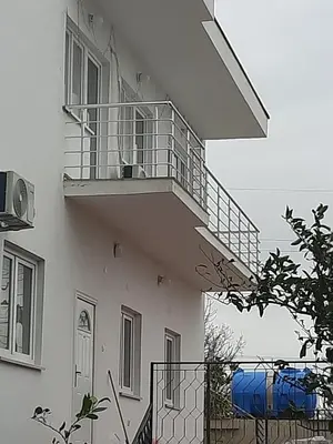 a white building with a balcony with a blue sheet at Mariyka Apartaments 2 in Sutomore
