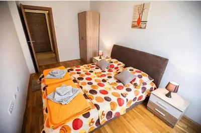 a bedroom with a large bed with an orange comforter at Nakiiii apartmanii in Podgorica