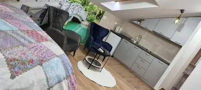 a bedroom with a bed and chairs and a kitchen at Nakiiii apartmanii in Podgorica