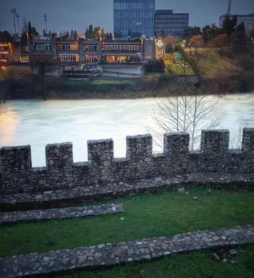 a stone fence in front of a body of water at Nakiiii apartmanii in Podgorica