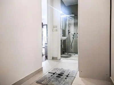 a hallway with a bathroom with a shower and a mirror at Jasna's Old Town Apartment in Podgorica