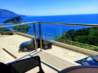 a balcony with a view of the ocean and a car at Hillside Apartment with Infinity Pool and Sea View in Budva