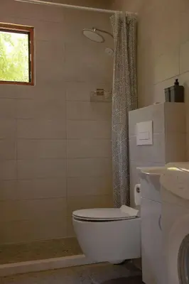 a bathroom with a toilet and a shower with a window at River house Bonaca in Ulcinj