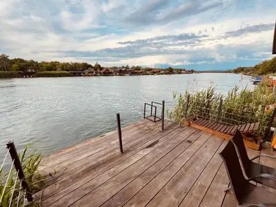 a wooden dock with chairs on the side of a lake at River house Bonaca in Ulcinj