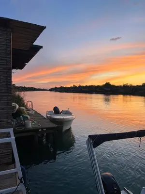 a boat on the water at a dock with a sunset at Barbana Cottage , Ada Bojana in Ulcinj