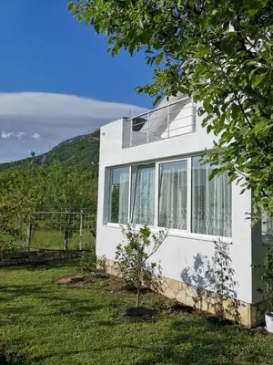 a white house with a hill in the background at Schmidt in Lastva