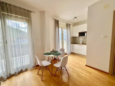 a dining room with a table and chairs and a kitchen at Palma in Budva