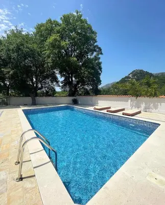a swimming pool with blue water and trees in the background at STARS RESIDENCE in Petrovac na Moru