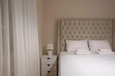a bedroom with a bed with white sheets and a lamp at Luxury Apartments Montesan in Sveti Stefan