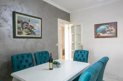 a dining room with a white table and blue chairs at Luxury Apartments Montesan in Sveti Stefan