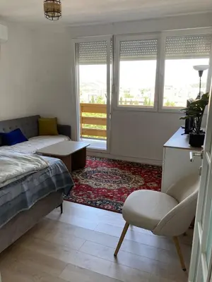 a bedroom with a bed and a chair and windows at City View Studio in Podgorica