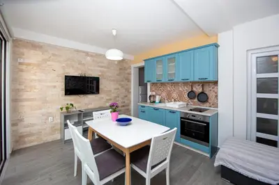 a kitchen with blue cabinets and a table and chairs at Apartments AriaSana-5m from the beach in Dobra Voda
