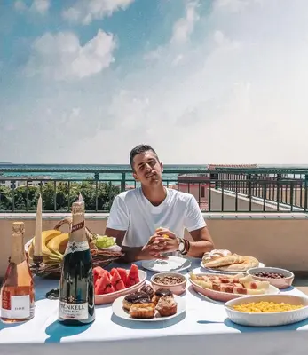 a man sitting at a table with food and drinks at Guest House Medin in Petrovac na Moru