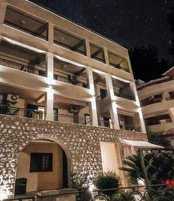 a large white building with an archway at night at Guest House Medin in Petrovac na Moru