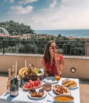 a woman sitting at a table with food at Guest House Medin in Petrovac na Moru
