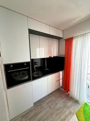 a kitchen with white cabinets and a red curtain at D&D in Bar