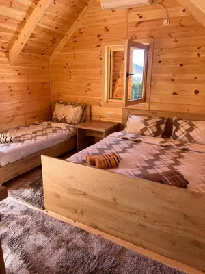 a bedroom with two beds in a log cabin at Cozy bungallows in Podgorica