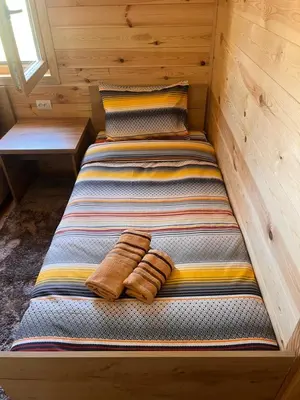 a bed in a wooden room with two towels on it at Cozy bungallows in Podgorica