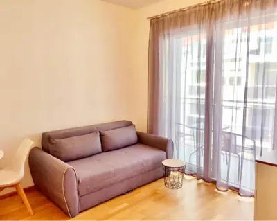 a couch in a living room with a large window at Apartmani More in Budva