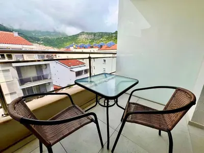 a glass table and two chairs on a balcony at Apartmani More in Budva