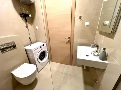 a bathroom with a toilet sink and a washing machine at Apartmani More in Budva