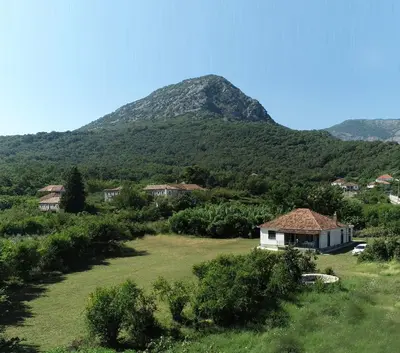 a house in a field with a mountain in the background at Casa L in Ulcinj