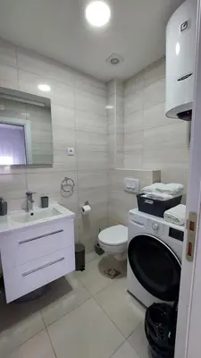 a bathroom with a toilet and a sink and a washing machine at D&M Studio Apartments in Bar