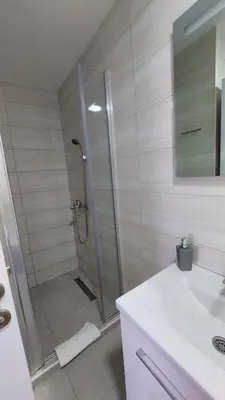 a bathroom with a shower and a white sink at D&M Studio Apartments in Bar
