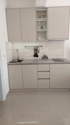 a white kitchen with white cabinets and a sink at D&M Studio Apartments in Bar